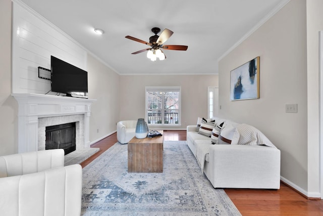 living room featuring ceiling fan, ornamental molding, a fireplace, and hardwood / wood-style floors