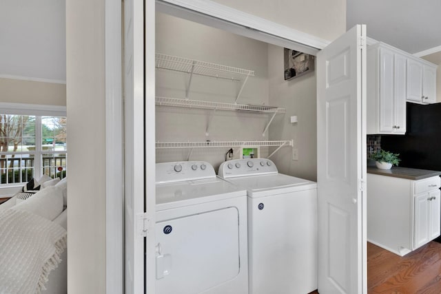 clothes washing area with ornamental molding, washer and dryer, and dark wood-type flooring