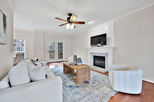 living room with hardwood / wood-style flooring, a fireplace, crown molding, and ceiling fan