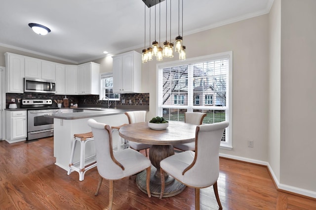 dining space with an inviting chandelier, ornamental molding, dark hardwood / wood-style floors, and sink