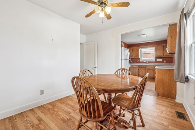 dining room with ceiling fan, sink, and light hardwood / wood-style floors