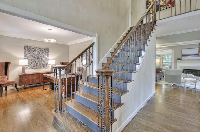 stairs with hardwood / wood-style flooring, ornamental molding, and a high ceiling