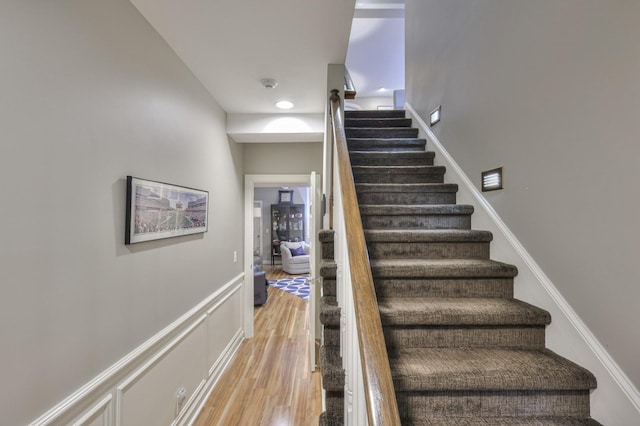 staircase featuring a wainscoted wall, a decorative wall, and wood finished floors