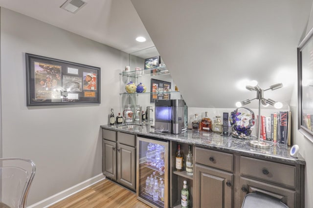 bar with beverage cooler, a sink, visible vents, light wood-style floors, and a bar