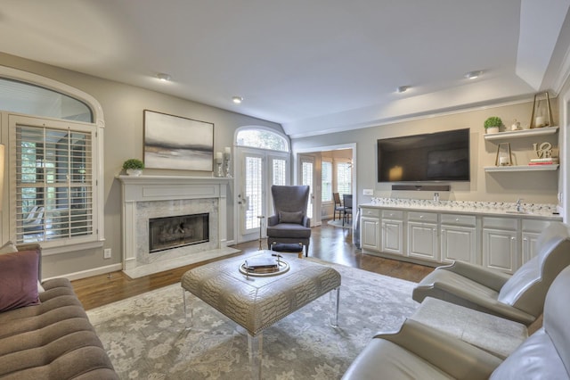 living room featuring a high end fireplace, baseboards, and wood finished floors