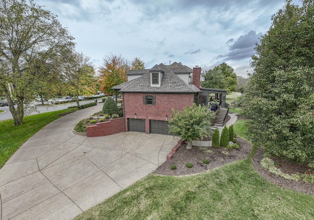 view of side of home with a garage, concrete driveway, stairway, a yard, and brick siding