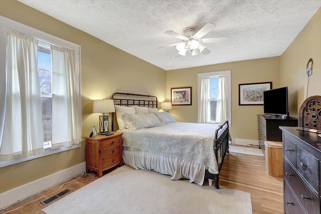 bedroom with ceiling fan, light hardwood / wood-style flooring, and a textured ceiling