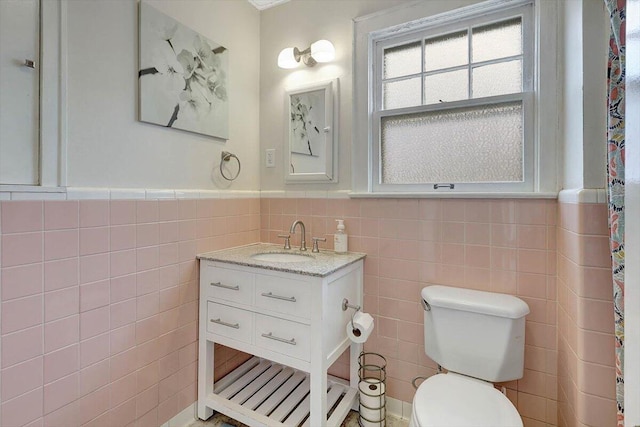 bathroom featuring tile walls, vanity, and toilet