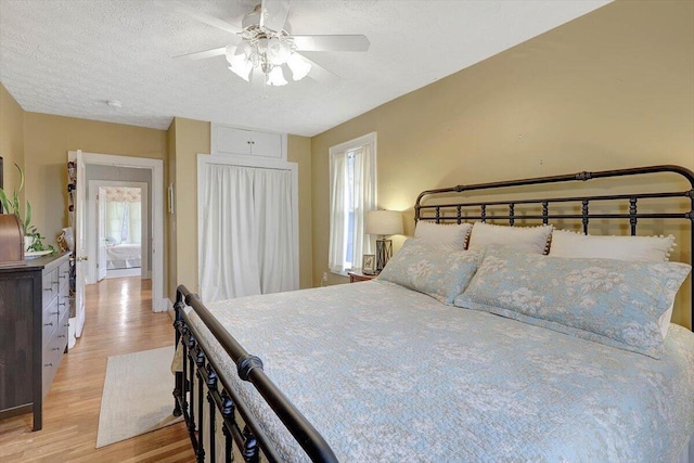 bedroom with ceiling fan, a textured ceiling, and light wood-type flooring