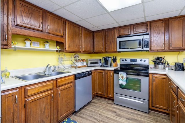 kitchen featuring appliances with stainless steel finishes, sink, a paneled ceiling, and light hardwood / wood-style floors