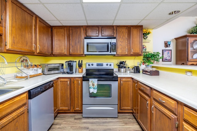 kitchen featuring a drop ceiling, light wood-type flooring, and appliances with stainless steel finishes