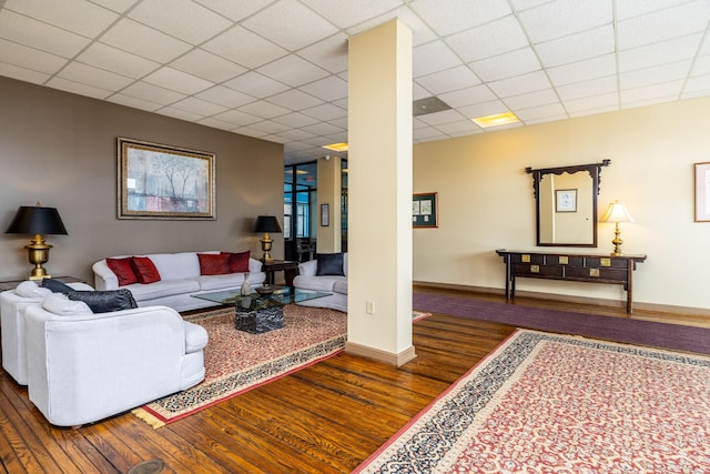 living room featuring dark wood-type flooring and a drop ceiling