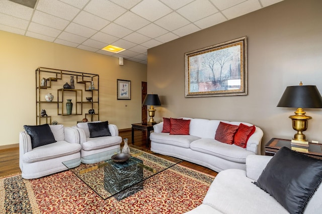 living room with a drop ceiling and wood-type flooring