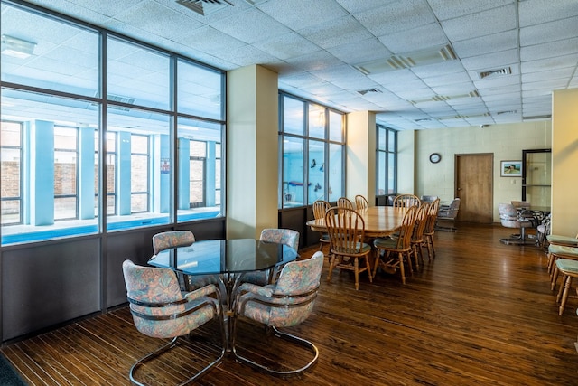 dining space with dark wood-type flooring and a drop ceiling