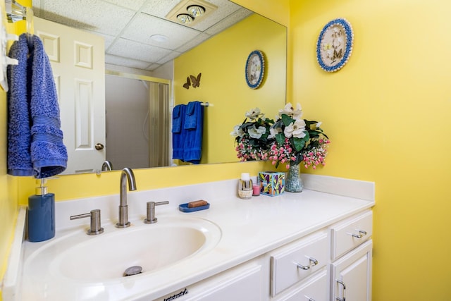 bathroom featuring vanity, a shower with door, and a drop ceiling