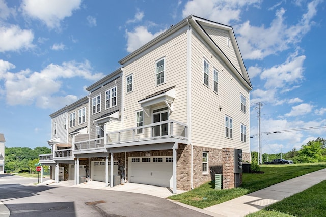 view of front facade featuring a garage, a front lawn, and a balcony