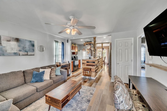 living room with ceiling fan, a healthy amount of sunlight, and light wood-type flooring