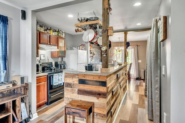 kitchen featuring white refrigerator, black range with electric stovetop, a notable chandelier, and light hardwood / wood-style floors