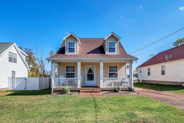 cape cod-style house featuring covered porch and a front lawn