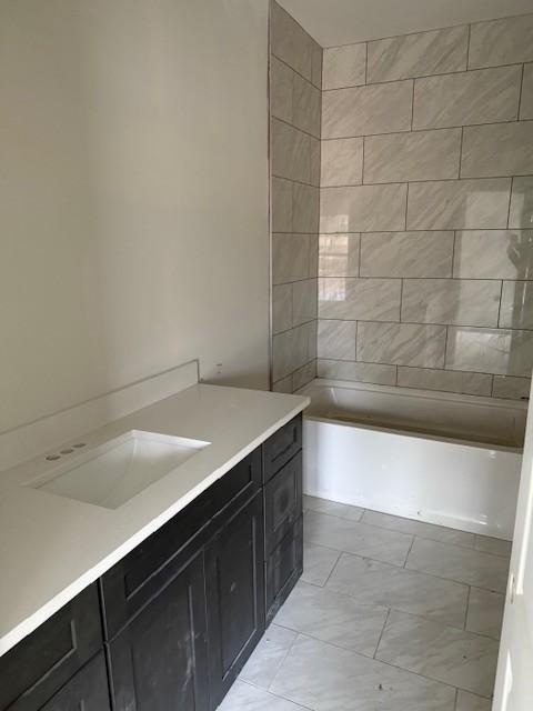 bathroom featuring vanity and tiled shower / bath