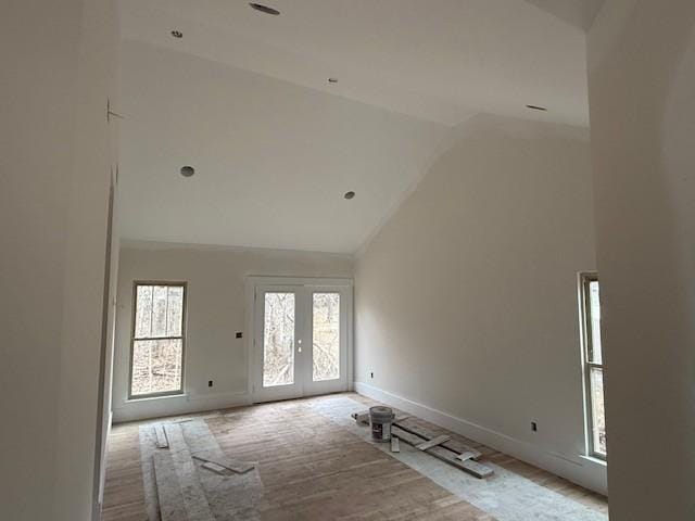 spare room with hardwood / wood-style floors, high vaulted ceiling, and french doors