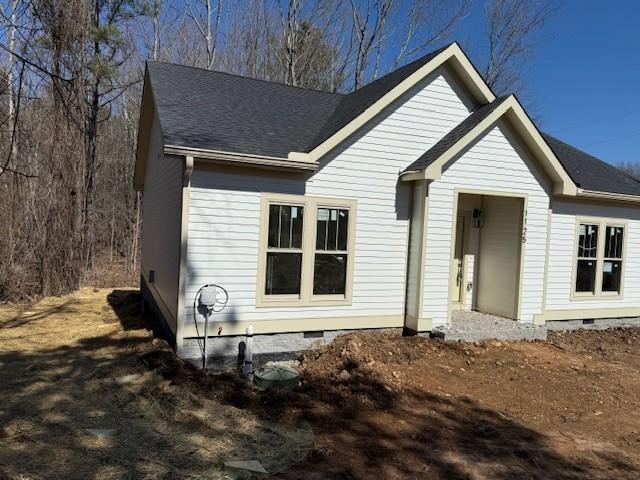 rear view of house featuring roof with shingles and crawl space