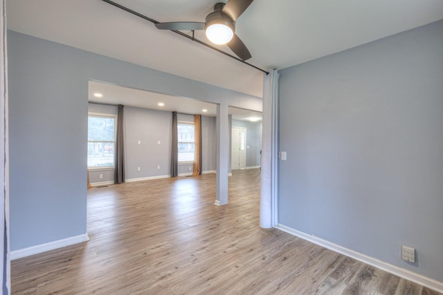 empty room with ceiling fan and light hardwood / wood-style floors