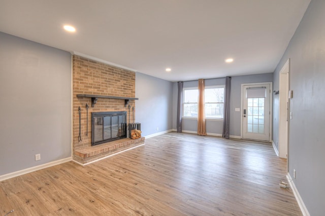 unfurnished living room with a brick fireplace and light hardwood / wood-style flooring