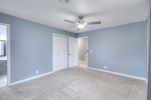 unfurnished bedroom featuring ceiling fan, light colored carpet, ensuite bathroom, and a closet