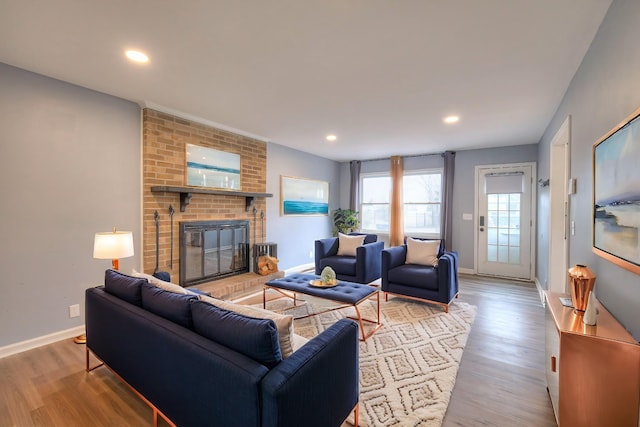 living room with light hardwood / wood-style floors and a brick fireplace