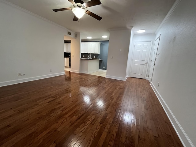 unfurnished living room featuring ornamental molding, dark hardwood / wood-style floors, sink, and ceiling fan