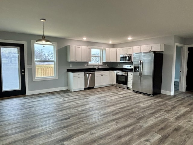 kitchen with sink, decorative light fixtures, light wood-type flooring, appliances with stainless steel finishes, and white cabinets