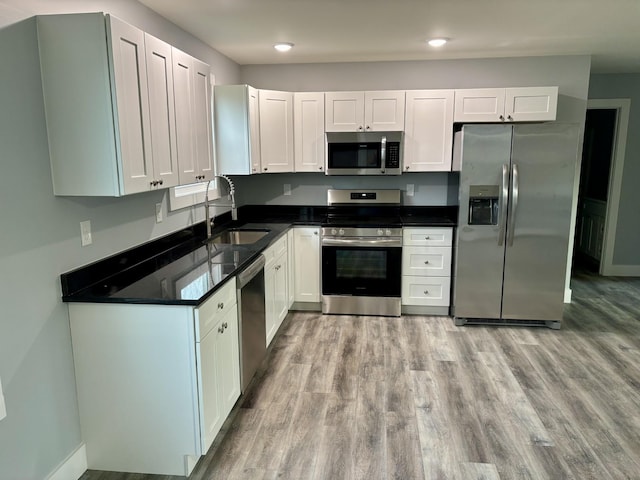 kitchen featuring stainless steel appliances, sink, white cabinets, and light wood-type flooring