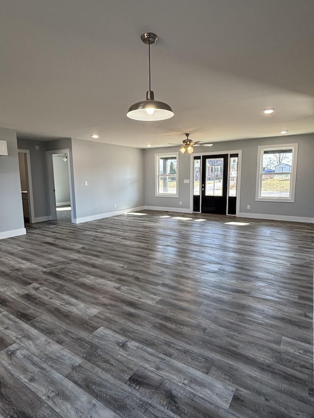 unfurnished living room with dark hardwood / wood-style floors and ceiling fan