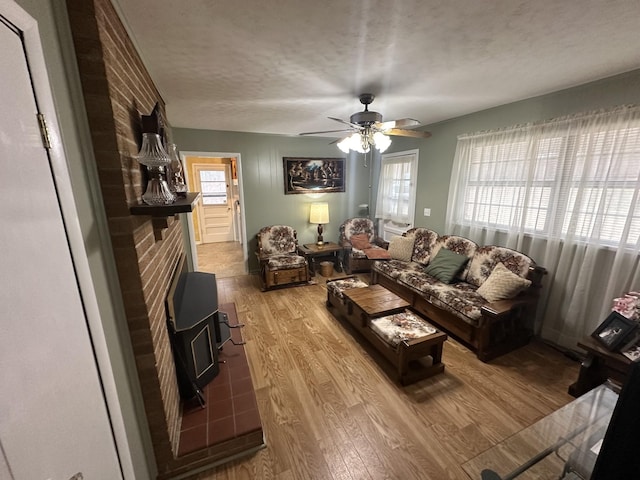 living room with a textured ceiling, light hardwood / wood-style floors, a wood stove, and a wealth of natural light