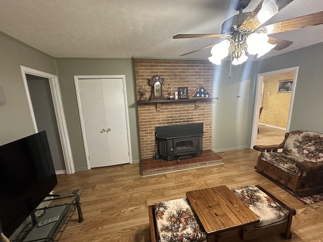 living room with hardwood / wood-style floors, a textured ceiling, ceiling fan, and a wood stove