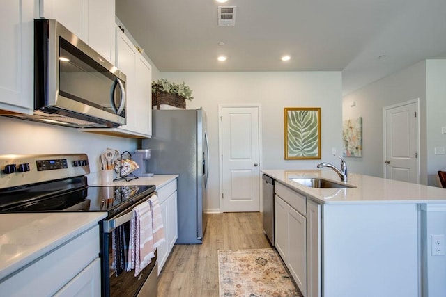 kitchen featuring white cabinetry, appliances with stainless steel finishes, a kitchen island with sink, and sink