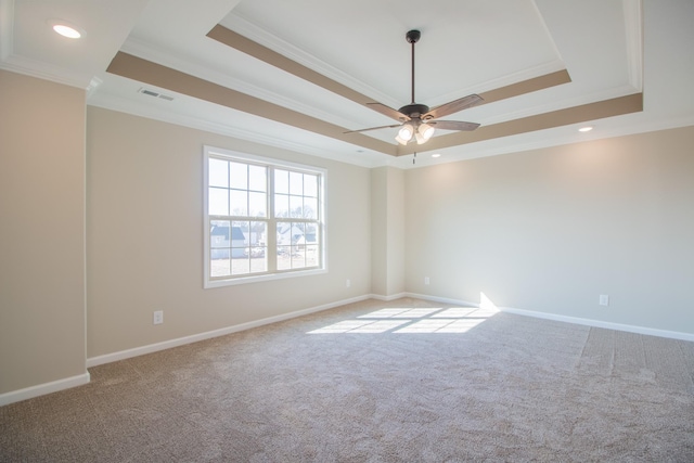 spare room with crown molding, ceiling fan, a raised ceiling, and light carpet