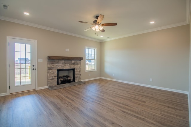 unfurnished living room with crown molding, a stone fireplace, hardwood / wood-style floors, and ceiling fan