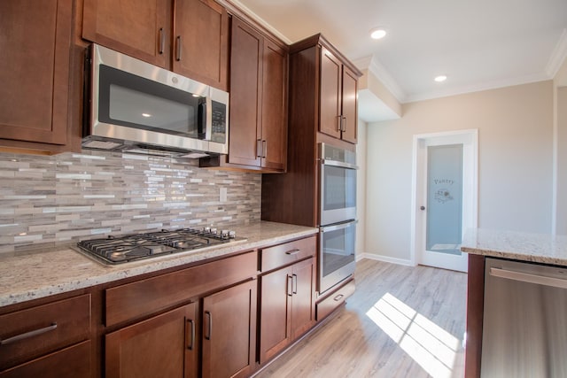 kitchen featuring backsplash, ornamental molding, stainless steel appliances, light stone countertops, and light hardwood / wood-style flooring