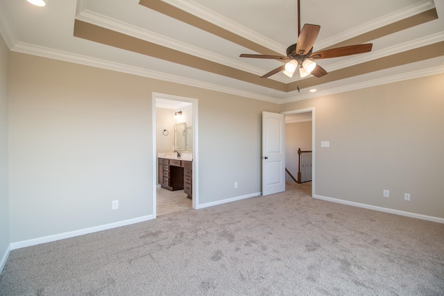 unfurnished bedroom with ornamental molding, a tray ceiling, ensuite bathroom, and light carpet