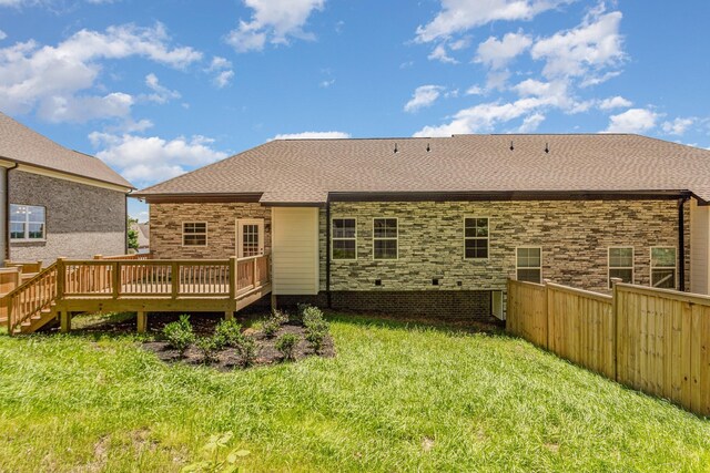 rear view of house with a yard, roof with shingles, fence, and a wooden deck