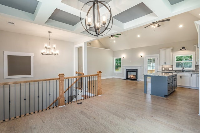 kitchen featuring ceiling fan with notable chandelier, a breakfast bar, white cabinets, open floor plan, and a center island