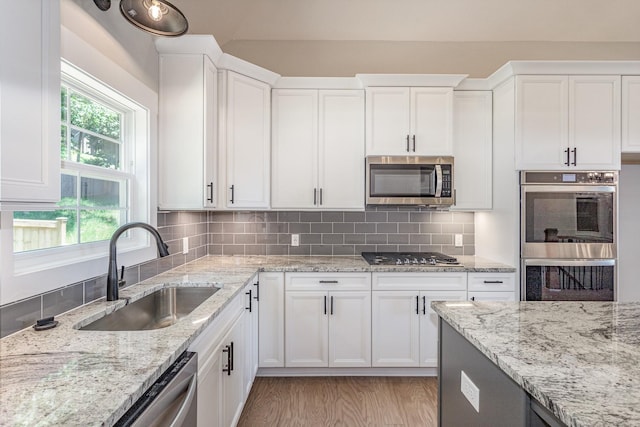 kitchen featuring appliances with stainless steel finishes, tasteful backsplash, sink, white cabinets, and light stone counters