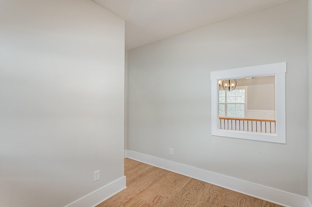 empty room with light wood-style floors, baseboards, and a chandelier