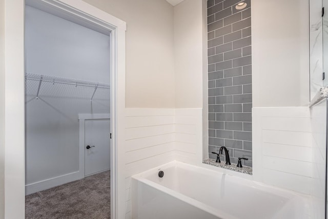 bathroom featuring a bathtub and a walk in closet