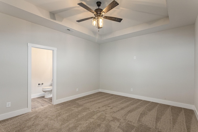 unfurnished room with light colored carpet, ceiling fan, and a tray ceiling