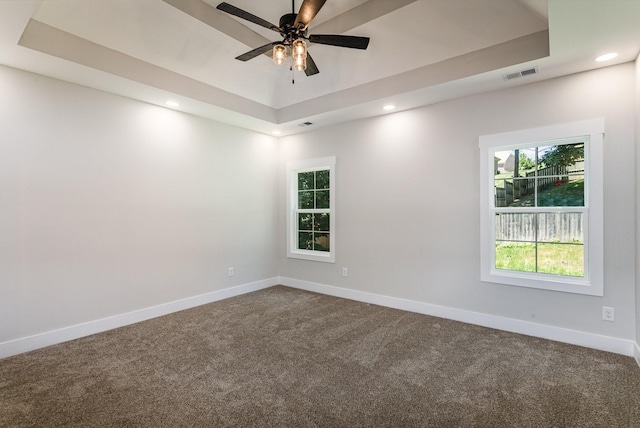 carpeted empty room with ceiling fan and a tray ceiling