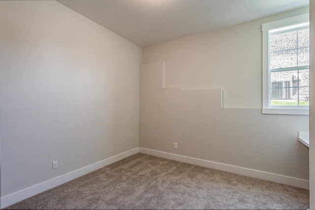 spare room featuring baseboards and light colored carpet