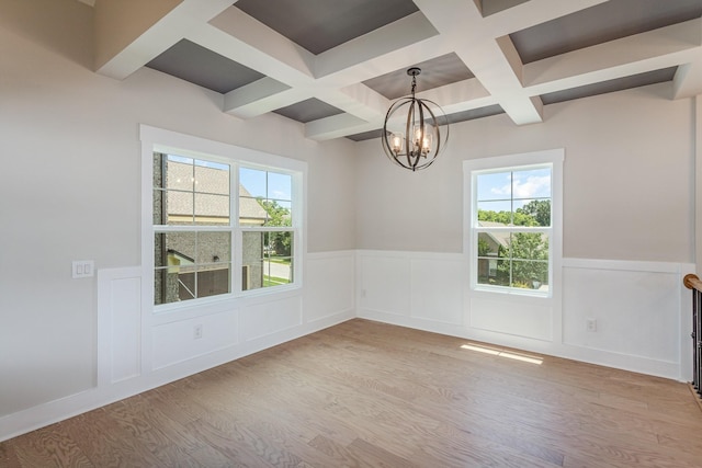 empty room featuring a chandelier, beam ceiling, a wainscoted wall, and wood finished floors